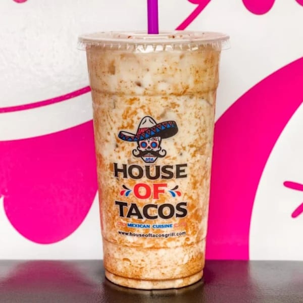 Horchata drink from House of Tacos Grill with a purple straw against a pink and white background.