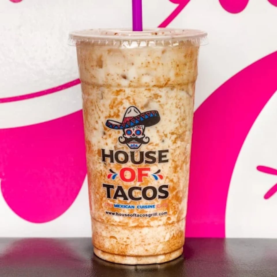 A House of Tacos Grill horchata drink with a purple straw, against a pink and white background.