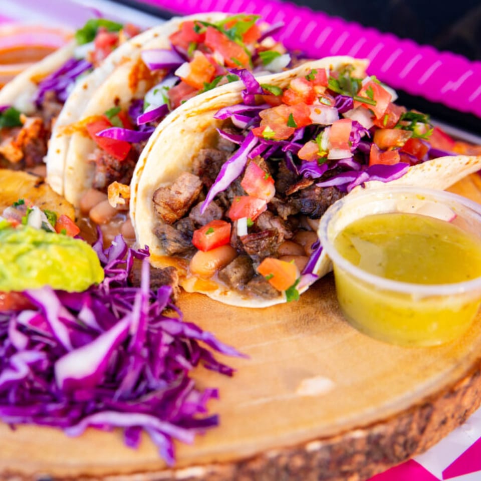 Three House of Tacos Grill tacos with meat, beans, red cabbage, pico de gallo, guacamole, and salsa.