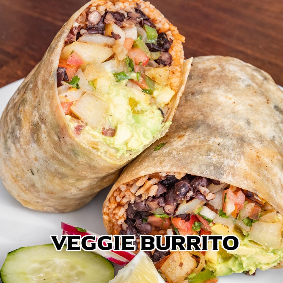 Two halves of a veggie burrito filled with rice, black beans, potatoes, and guacamole.
