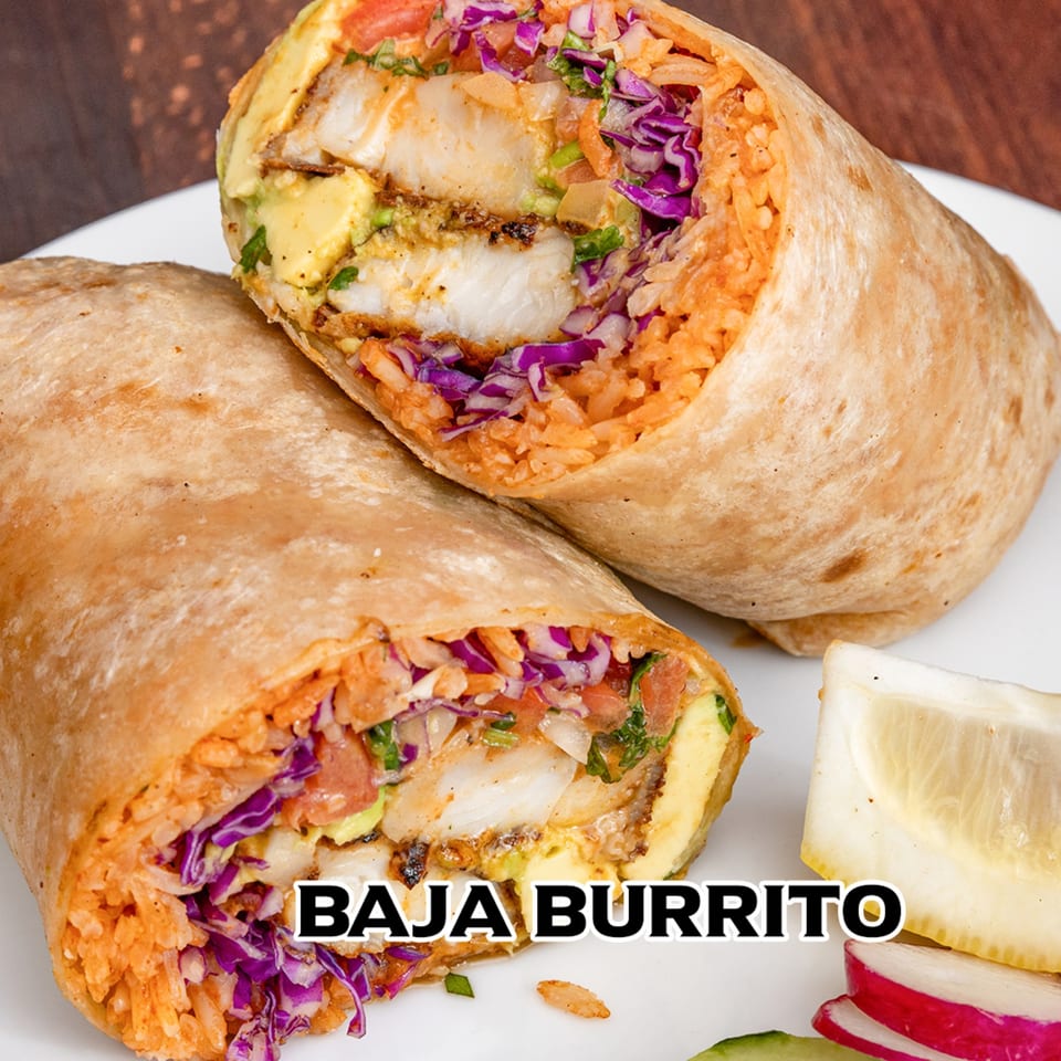 A Baja Burrito from House of Tacos Grill, sliced in half, revealing fish, rice, and purple cabbage.