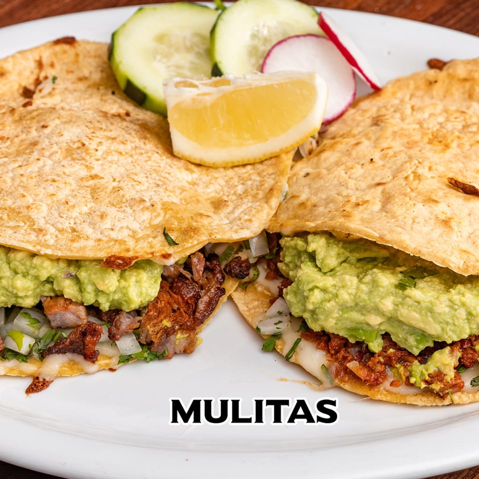 Two mulitas from House of Tacos Grill, filled with meat and guacamole, garnished with cucumber, radish, and lemon.