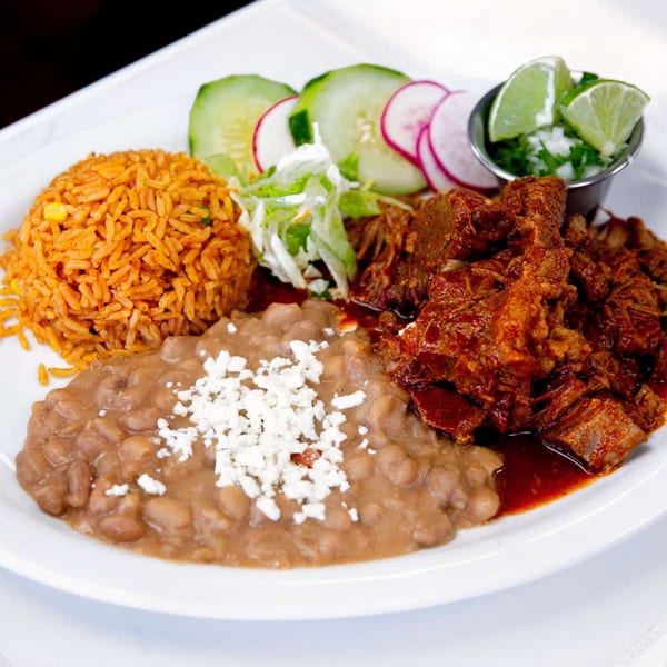 Mexican dish with red rice, refried beans with cheese, saucy red meat, and a side salad.