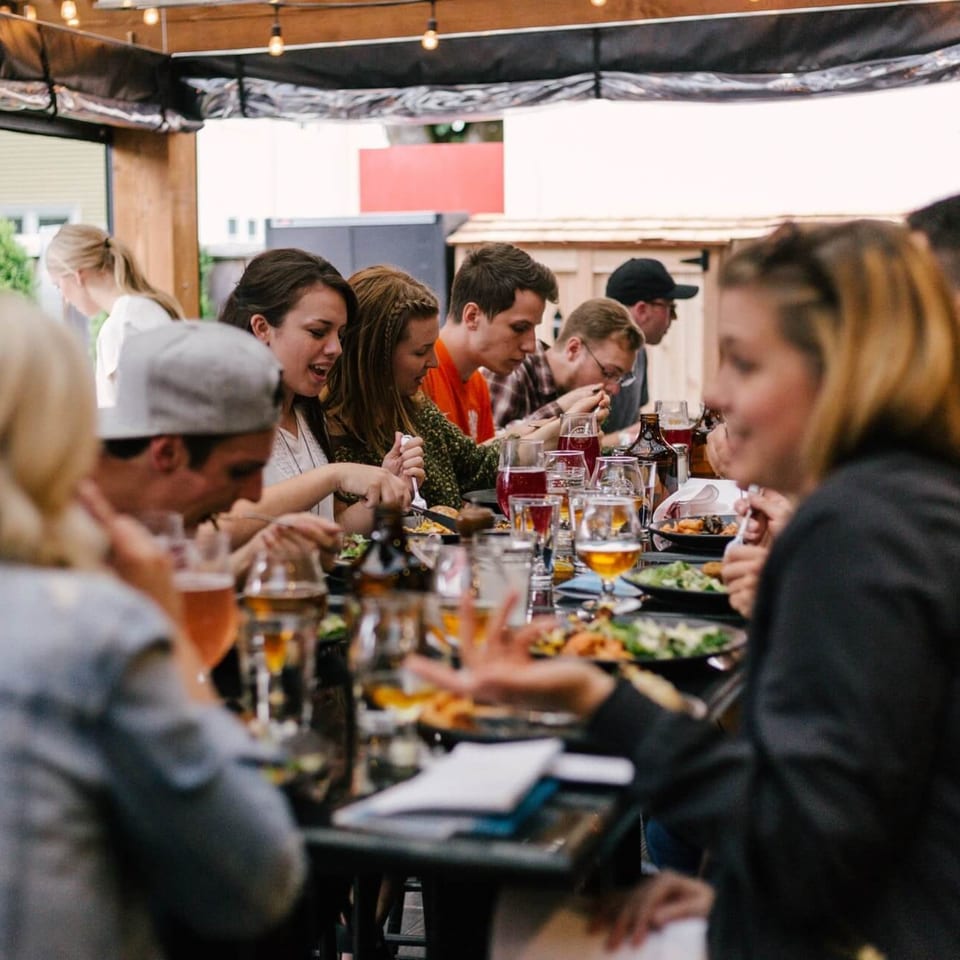 Friends enjoying Mexican food and drinks together at an outdoor restaurant patio.