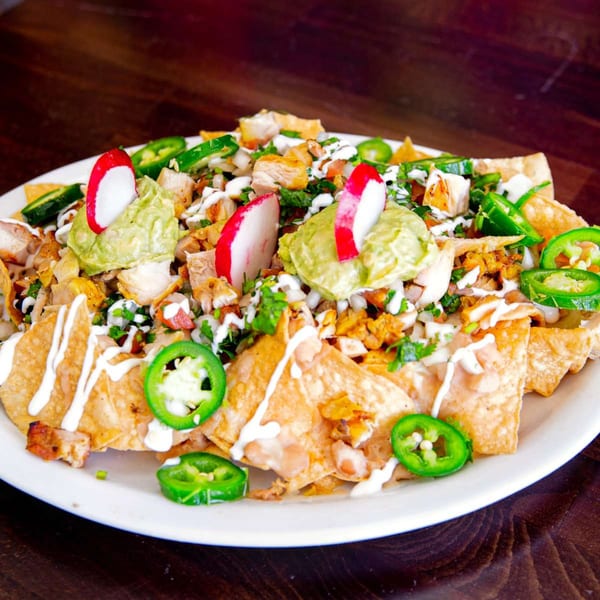 Chicken nachos from House of Tacos Grill, topped with guacamole, radishes, jalapeños, and crema.