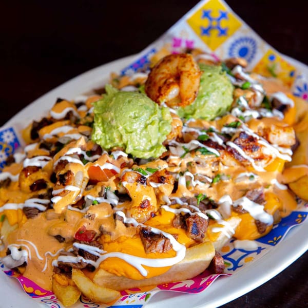 Loaded Mexican fries with steak, shrimp, guacamole, cheese sauce, and sour cream.