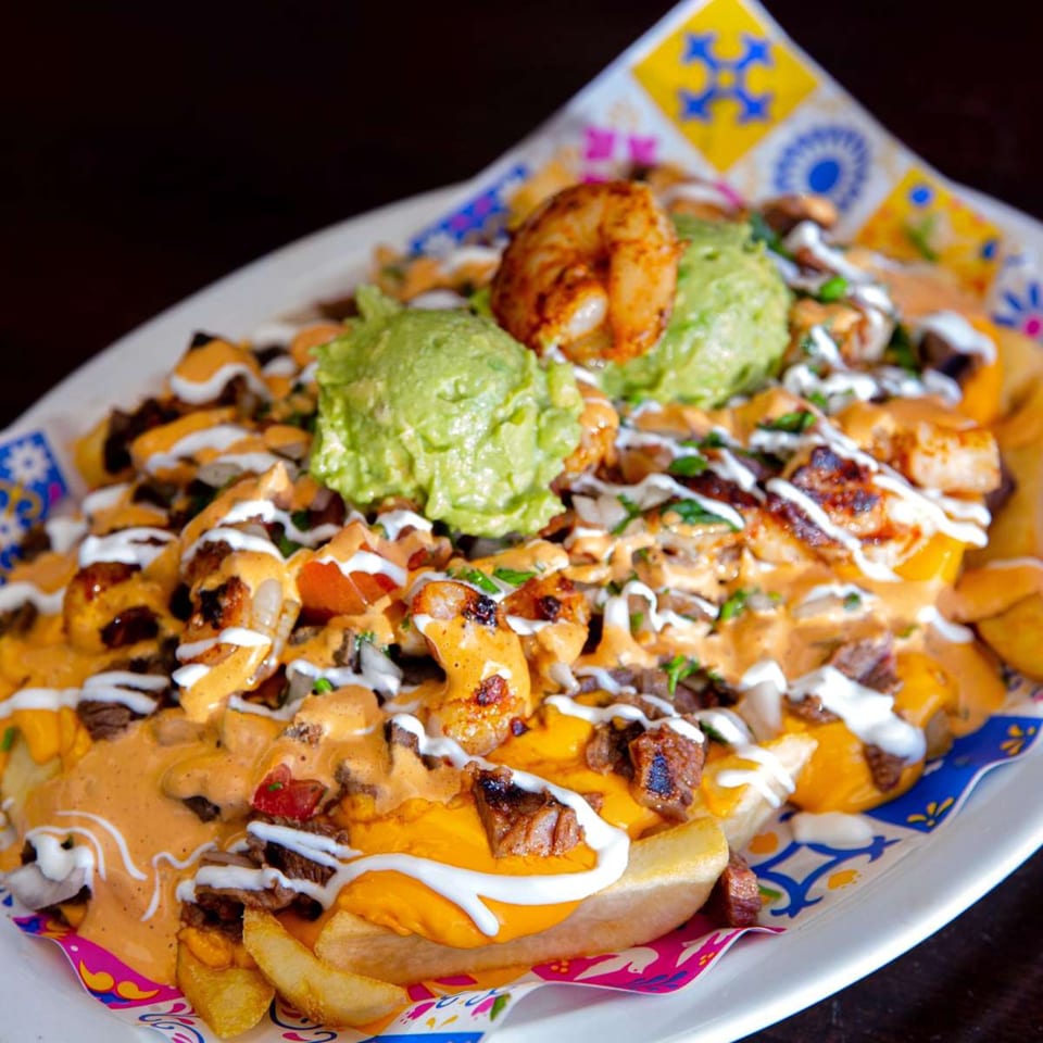 Loaded Mexican fries with steak, shrimp, guacamole, cheese sauce, and sour cream.