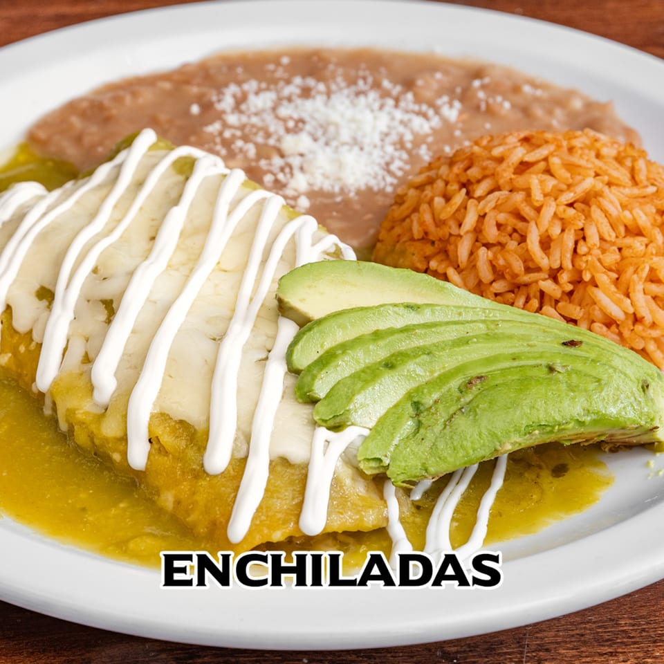 Mexican enchiladas with green sauce, sour cream, avocado, rice, and refried beans on a white plate.